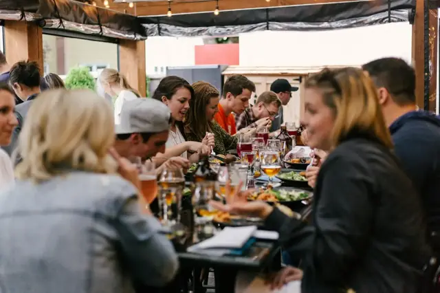 A full table of friends laughing over dinner