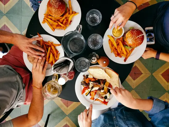 Friends sharing burgers, fries and tacos from above